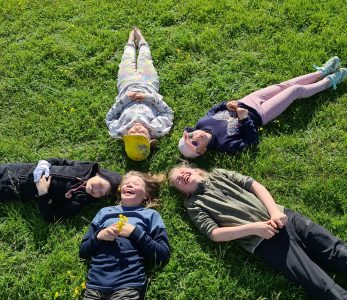 Ryhmä nuoria makaamassa nurmikolla Inarin Vasatokassa.