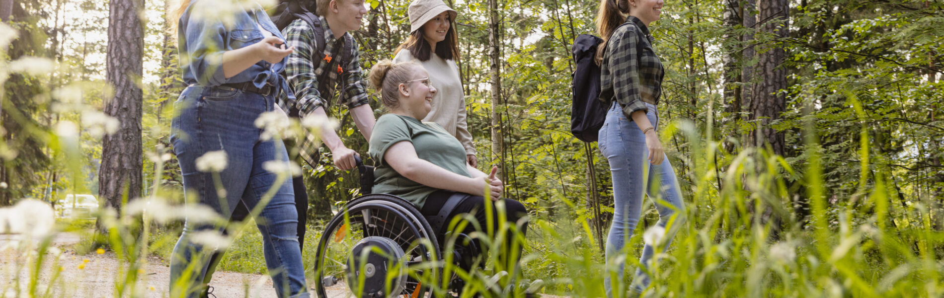 Ryhmä nuoria kulkee metsäpolkua pitkin, yksi heistä pyörätuolissa, leirikoulussa nuorisokeskus Vasatokassa.